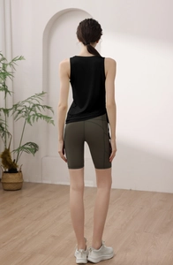 Detail view of black yoga tank top with side drawstrings and olive high-waist biker shorts