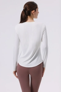 Detail view of white long sleeve yoga top with V-shaped stitching and breathable fabric