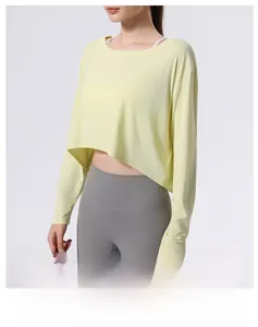Detail eines hellgelben, lockeren Crop-Tops mit asymmetrischem Saum und atmungsaktivem Stoff