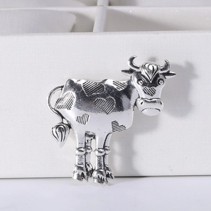 Macro shot of vintage silver cow brooch with heart patterns on a white jewelry display box