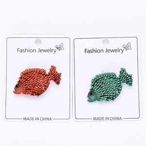 Detail of colorful fish brooches in orange and green with textured scale patterns