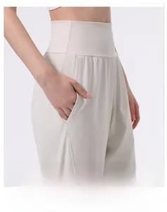 Close-up of wide high waistband on beige yoga pants showing tummy control side pocket