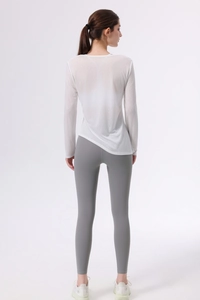 Dettaglio del top da yoga a maniche lunghe semitrasparente con orlo irregolare e leggings grigi