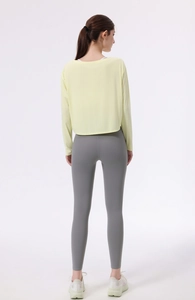 Rückansicht von lockerem gelbem Yoga-Oberteil und grauer Leggings mit hohem Bund