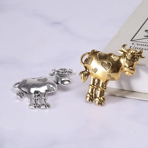 Vintage bull zodiac brooches in gold and silver alloy with heart relief on marble surface