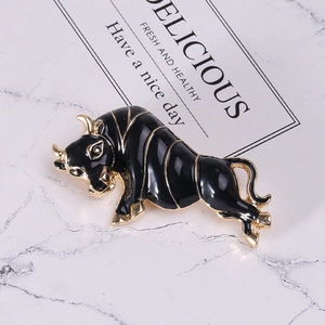 Detailed shot of vintage gold ox brooch with black enamel inlay on marble background