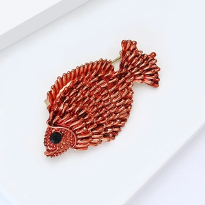 Vintage orange fish brooch with detailed scales and black gemstone eye on white background