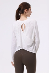 Dettaglio della maglia da yoga bianca a maniche lunghe con spacco posteriore e tessuto jacquard