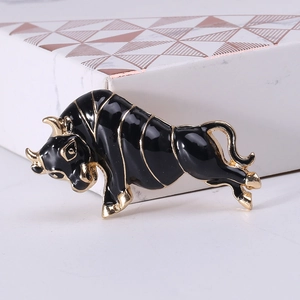 Macro shot of black enamel bull brooch with gold-tone edges on marble display