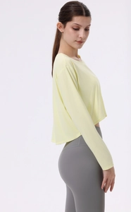 Detail eines locker sitzenden Langarm-Yoga-Crop-Tops aus hellgelbem, atmungsaktivem Stoff