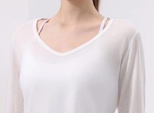 Dettaglio della maglia da yoga bianca con scollo a V e trama traspirante in cotone Lyocell