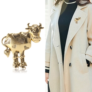 Vintage gold ox brooch with heart patterns shown on white background and model coat