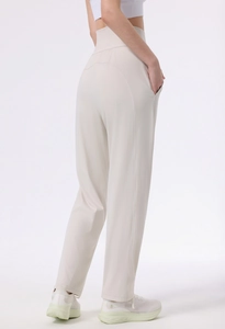 Detail view of high-waisted yoga pants in cream white featuring side pockets and loose fit