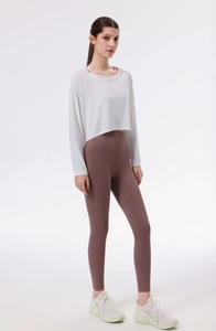 Detail eines lockeren weißen Seiden-Yoga-Oberteils mit mauvefarbenen Fitness-Leggings