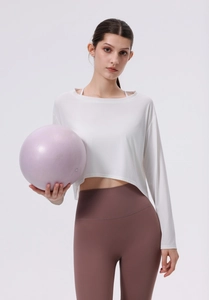 Detail eines lockeren weißen Yoga-Oberteils und brauner Leggings mit hoher Taille