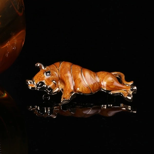Detailed view of vintage gold bull brooch with brown enamel inlay on black reflective background