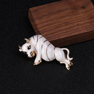 Detail of a bull brooch featuring white enamel finish and golden metal accents