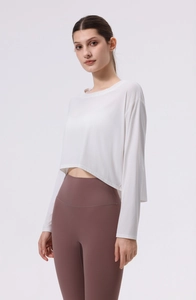 Detail des weißen langärmeligen Yoga-Crop-Tops mit atmungsaktivem Stoff und geschwungenem Saum