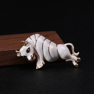 Macro detail of bull brooch featuring white enamel and golden metal finish