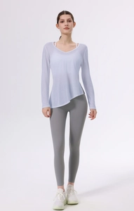 Dettaglio del top da yoga con scollo a V, bordo asimmetrico e leggings grigi