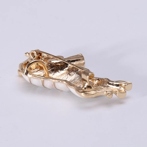 Back view of a gold alloy zodiac ox brooch with white enamel inlay and safety pin
