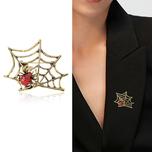 Detail of vintage gold spider web brooch with red rhinestones on a black suit lapel