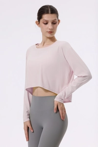 Detail eines hellrosa gerippten Yoga-Crop-Tops mit langen Ärmeln und lockerem Stoff