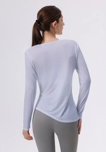 Dettaglio del tessuto traspirante e dell'orlo asimmetrico sulla maglia da yoga a maniche lunghe