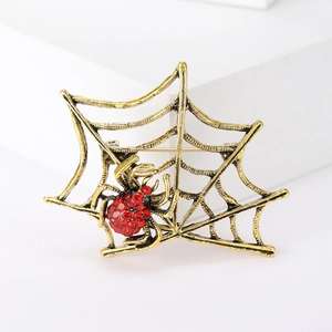 Detailed close-up of retro bronze spider web brooch with vibrant red rhinestones