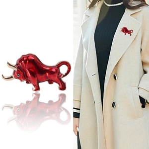 Dynamic red enamel bull brooch with gold accents shown on white background and coat lapel