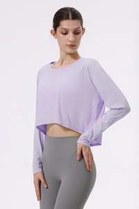 Detail von lavendelfarbenem Langarm-Yoga-Crop-Top und grauer High-Waist-Hose am Model