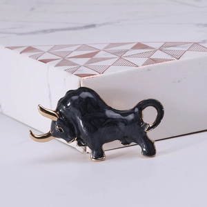 Detailed close-up of a bull-shaped brooch with black enamel marble finish and gold plating