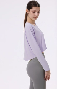 Detail eines locker sitzenden lila Yoga-Oberteils mit grauen Leggings mit hohem Bund