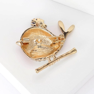 Back view of gold alloy bird brooch with frosted texture and secure safety pin fastener