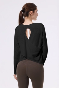 Dettaglio del design incrociato sulla schiena di un top da yoga nero a maniche lunghe con leggings