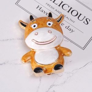 Detail of creative cartoon cow brooch with orange enamel inlay and golden metal edges