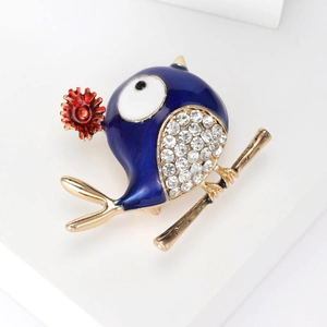 Detail of blue enamel bird brooch with evil eye motif and sparkling crystals on golden branch