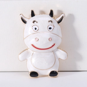 Close-up of cute cartoon ox brooch with white enamel finish and black horns detail