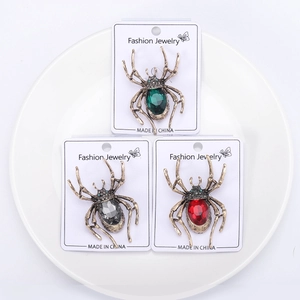 Drei Vintage-Spinne-Broschen aus Legierung mit bunten Edelsteinen auf einem weißen Teller