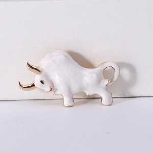 Detailed view of enamel bull brooch with gold accents and smooth white texture