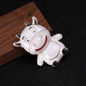 Close-up of cute enamel cow brooch featuring white finish with charming red smile details