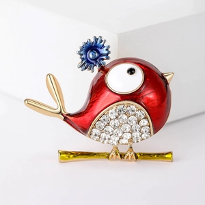 Close-up of red enamel bird brooch with blue flower detail and sparkling white rhinestones