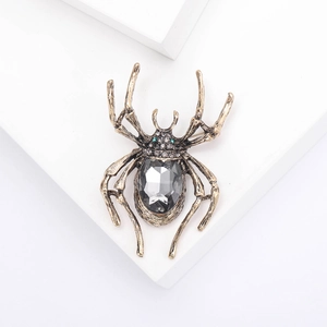 Vintage-Gold-Spinne-Brosche mit großem grauem Kristall und grünen Edelsteinaugen auf Stein