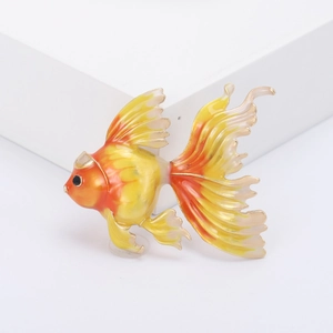 Élégante broche poisson rouge en émail doré avec dégradé orange vif sur un fond blanc pur