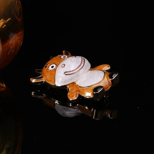 Macro detail of cute orange enamel cow brooch with black reflection on mirror background
