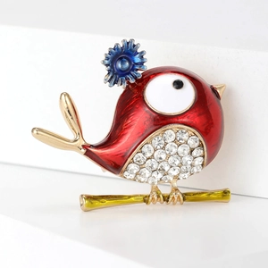 Exquisite red bird brooch with white crystals and blue floral detail on a gold branch