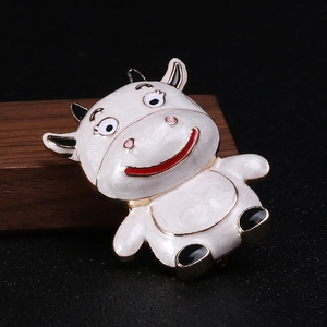 Detailed macro shot of a cute cartoon cow brooch with white enamel and metal finish