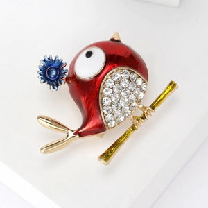 Detailed close-up of a red enamel bird brooch with white rhinestones on golden branch