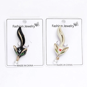 Close-up of enamel fox brooches with dangling pearls on a fashion jewelry card