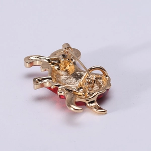 Back view of gold bull brooch with safety pin fastener and red enamel accents